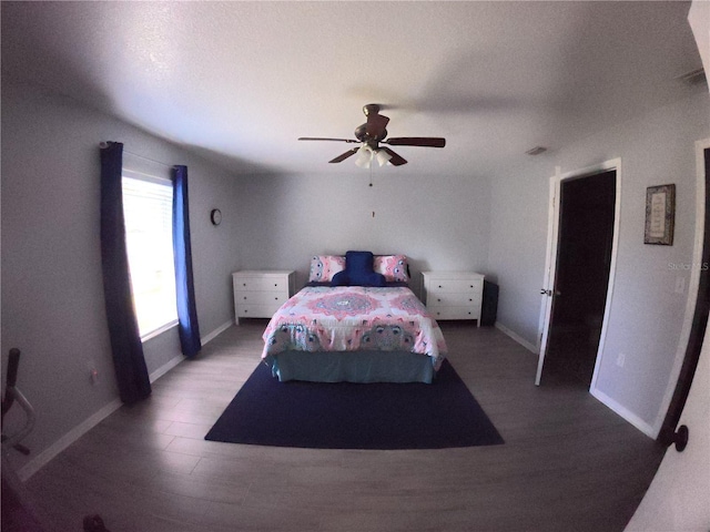 bedroom with ceiling fan, baseboards, and wood finished floors