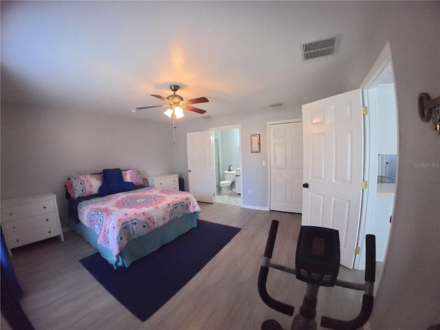 bedroom featuring visible vents, ensuite bathroom, ceiling fan, wood finished floors, and baseboards