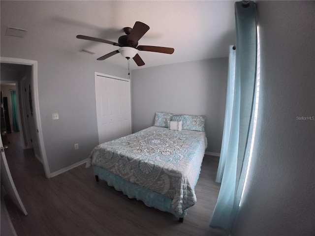 bedroom featuring baseboards, a closet, visible vents, and wood finished floors