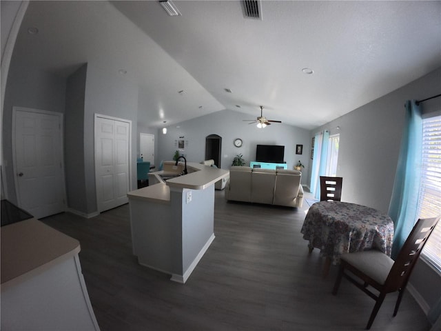 kitchen with arched walkways, dark wood finished floors, lofted ceiling, light countertops, and visible vents