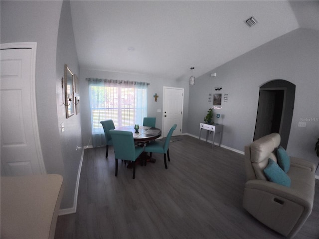 dining room featuring arched walkways, lofted ceiling, visible vents, wood finished floors, and baseboards