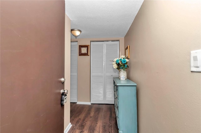 interior space with dark wood-style floors, a textured ceiling, and baseboards