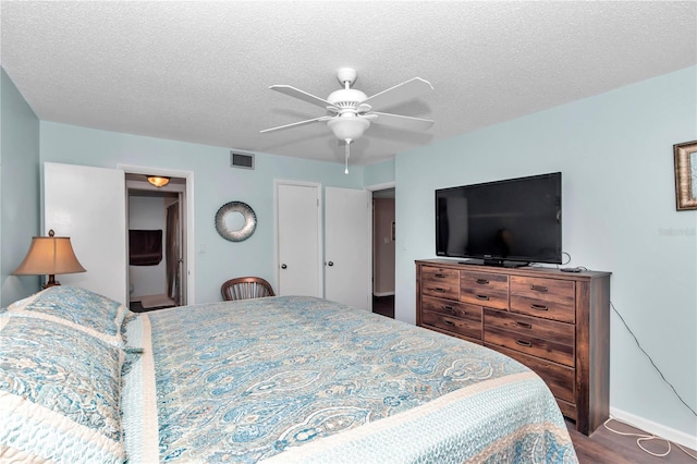 bedroom featuring baseboards, visible vents, ceiling fan, wood finished floors, and a textured ceiling