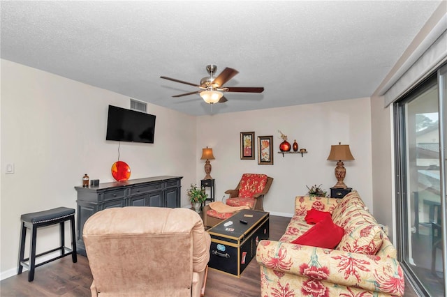 living area featuring a textured ceiling, dark wood-type flooring, visible vents, and a ceiling fan