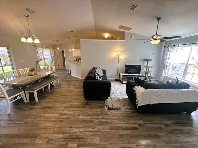 living room with a wealth of natural light, visible vents, vaulted ceiling, and dark wood-type flooring