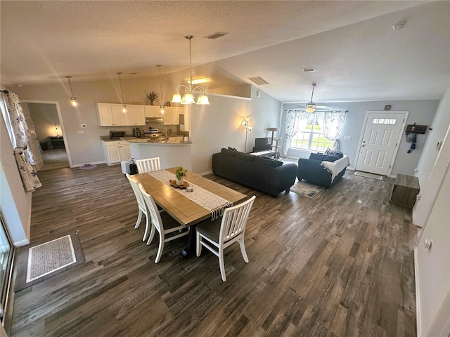 dining space featuring lofted ceiling, a textured ceiling, ceiling fan with notable chandelier, visible vents, and dark wood finished floors