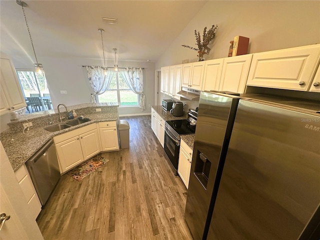 kitchen with stainless steel appliances, white cabinets, vaulted ceiling, a sink, and wood finished floors