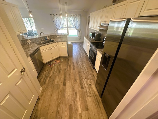 kitchen with appliances with stainless steel finishes, white cabinets, a sink, wood finished floors, and under cabinet range hood