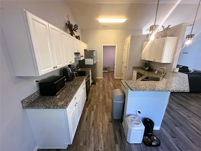 kitchen with a breakfast bar area, dark wood-type flooring, white cabinetry, a sink, and a peninsula