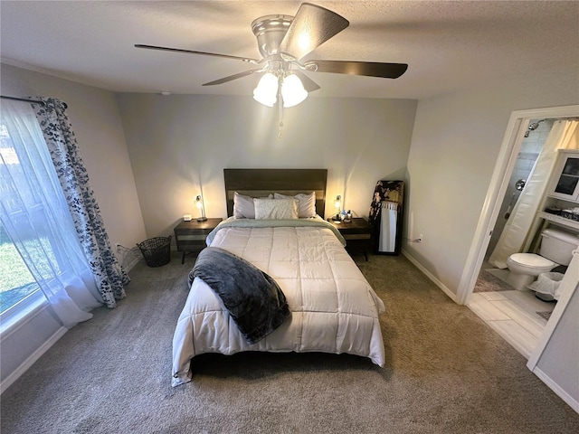 carpeted bedroom with ceiling fan, a textured ceiling, ensuite bathroom, and baseboards