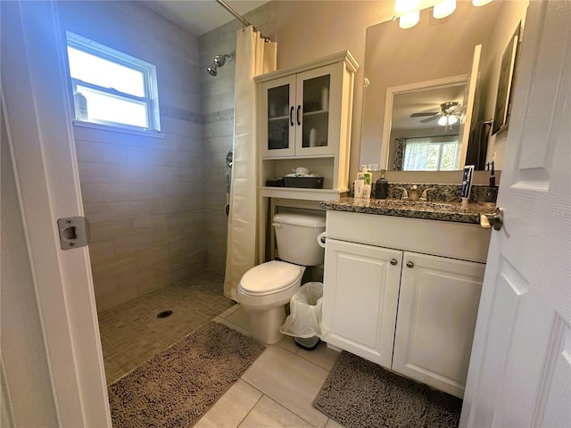 bathroom featuring vanity, a tile shower, toilet, and tile patterned floors