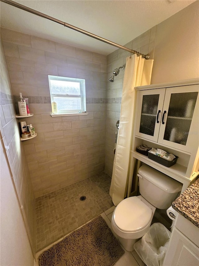 full bath with a tile shower, vanity, and toilet