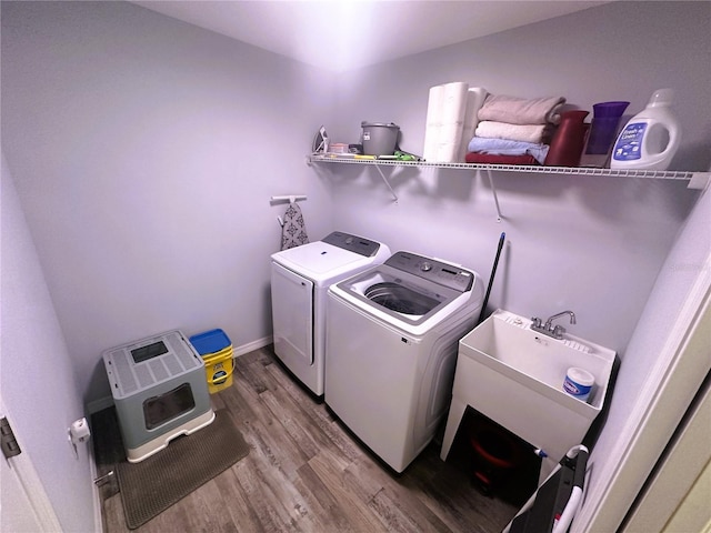 washroom with laundry area, baseboards, wood finished floors, washing machine and dryer, and a sink