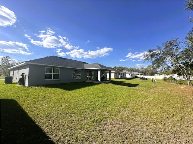 back of property featuring a yard, central air condition unit, and stucco siding