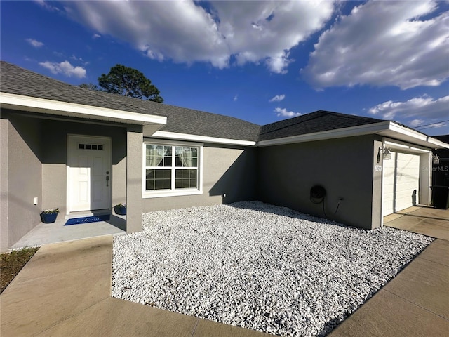 property entrance with a garage, roof with shingles, and stucco siding