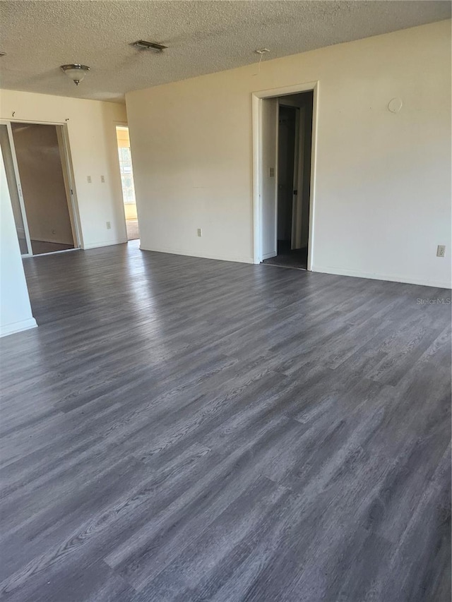 unfurnished room with dark wood-style floors, a textured ceiling, and visible vents