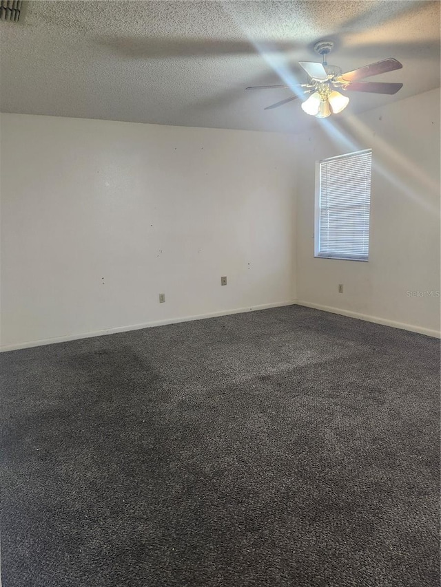 unfurnished room with a textured ceiling, visible vents, a ceiling fan, baseboards, and dark colored carpet