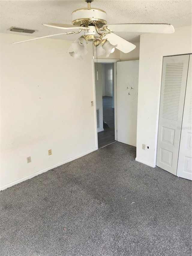 unfurnished room with ceiling fan, dark colored carpet, a textured ceiling, and visible vents