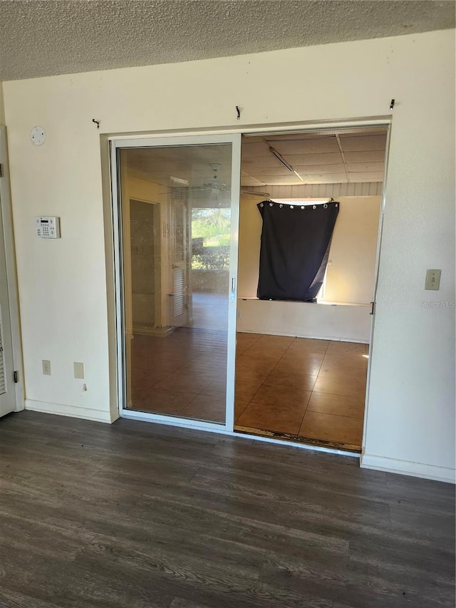 interior space with access to outside, a textured ceiling, baseboards, and wood finished floors