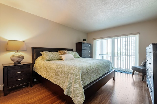 bedroom featuring access to outside, a textured ceiling, and wood finished floors