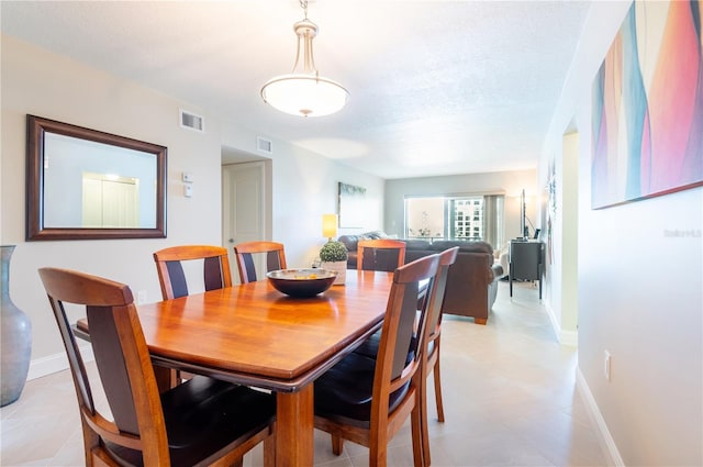 dining room with baseboards, visible vents, and a textured ceiling