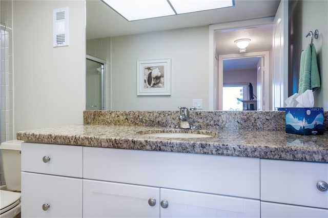 full bathroom featuring toilet, visible vents, a shower with shower door, and vanity