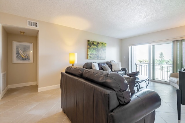 living area with visible vents, a textured ceiling, baseboards, and light tile patterned floors