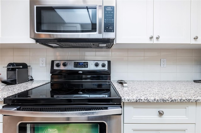 kitchen featuring white cabinets, stainless steel appliances, and backsplash