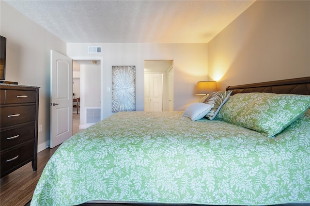 bedroom featuring a textured ceiling, dark wood-style flooring, and visible vents