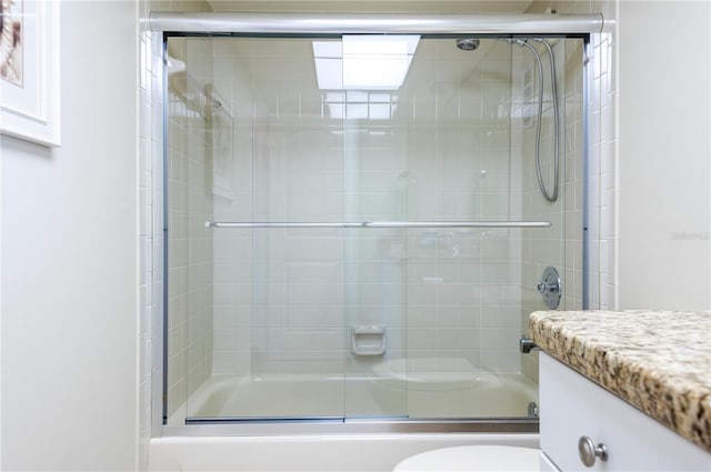 bathroom featuring combined bath / shower with glass door, vanity, and toilet