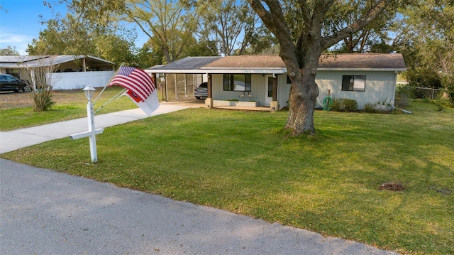 ranch-style home with an attached carport, concrete driveway, fence, and a front lawn