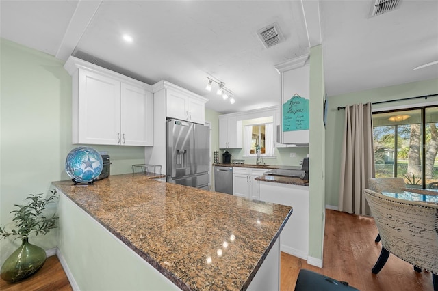 kitchen with appliances with stainless steel finishes, white cabinets, visible vents, and wood finished floors