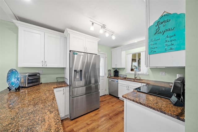 kitchen with a toaster, stainless steel appliances, white cabinets, a sink, and light wood-type flooring