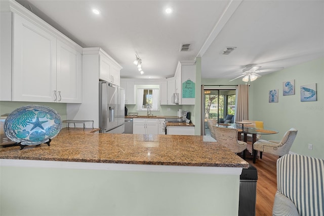 kitchen with visible vents, appliances with stainless steel finishes, wood finished floors, a peninsula, and a sink