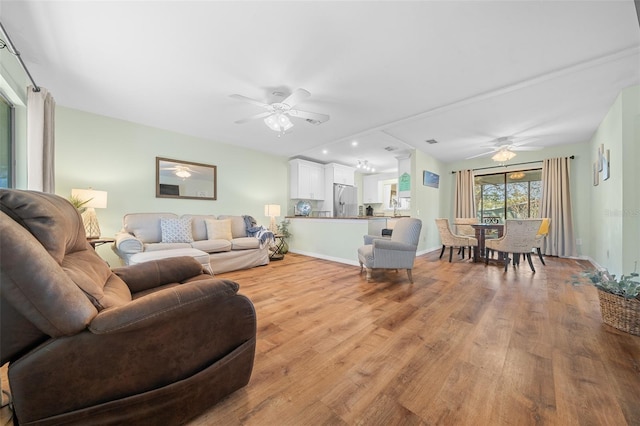 living area featuring baseboards, a ceiling fan, and wood finished floors