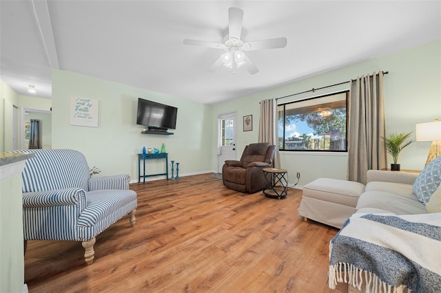 living room with light wood finished floors, ceiling fan, and baseboards