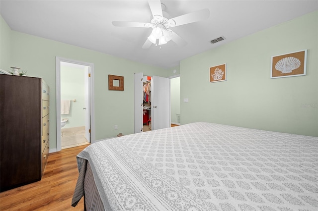 bedroom featuring visible vents, a spacious closet, a ceiling fan, connected bathroom, and light wood-type flooring