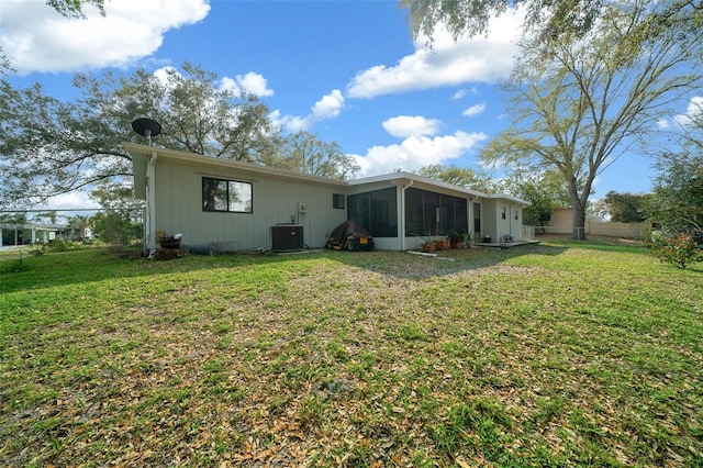 rear view of property featuring a sunroom, fence, a lawn, and central AC