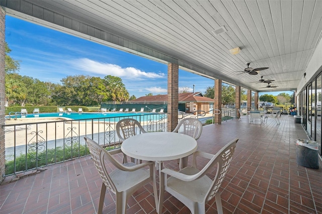 view of patio / terrace featuring ceiling fan, outdoor dining area, fence, and a community pool