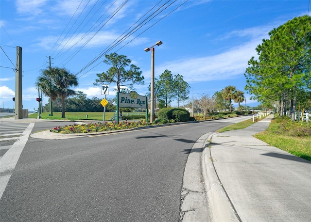 view of road featuring street lights, curbs, traffic signs, and sidewalks