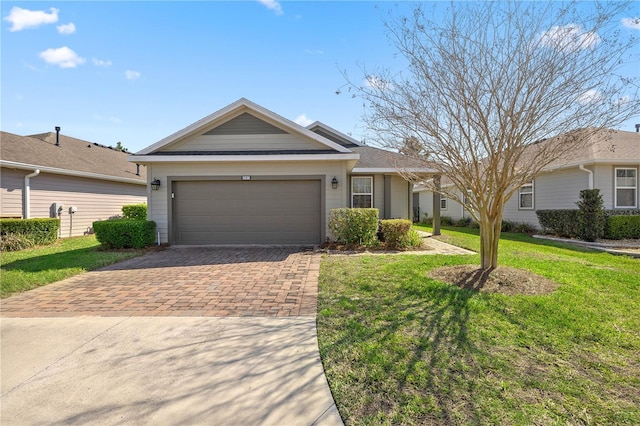 ranch-style home featuring a front yard, decorative driveway, and an attached garage