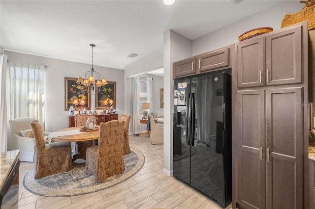 dining area featuring wood tiled floor, visible vents, a notable chandelier, and baseboards