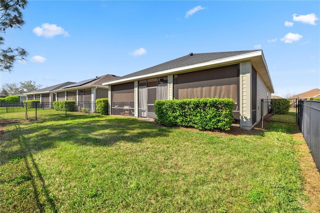 rear view of property featuring a lawn, a fenced backyard, and a sunroom