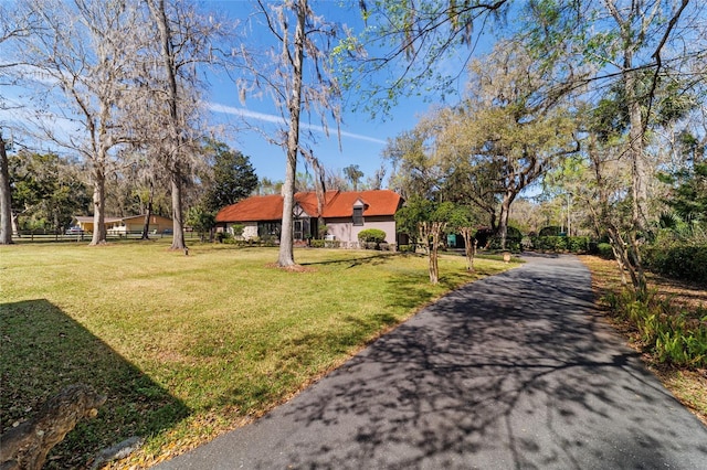 view of front facade featuring aphalt driveway, a front yard, and fence