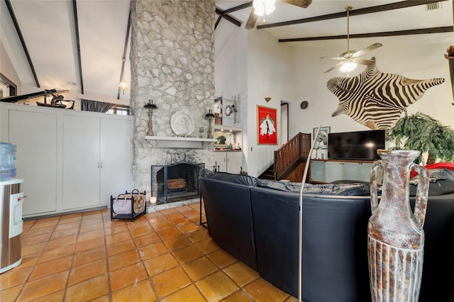 living area featuring ceiling fan, high vaulted ceiling, a stone fireplace, tile patterned flooring, and beamed ceiling