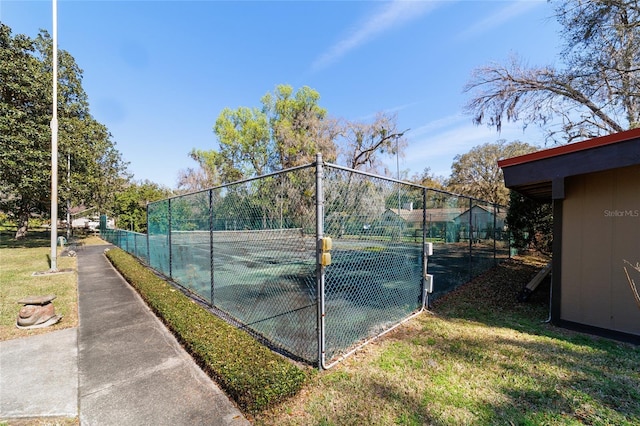 view of sport court with fence and a lawn