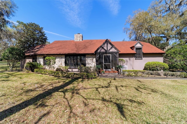 view of front of home featuring a tile roof, stone siding, stucco siding, a chimney, and a front yard