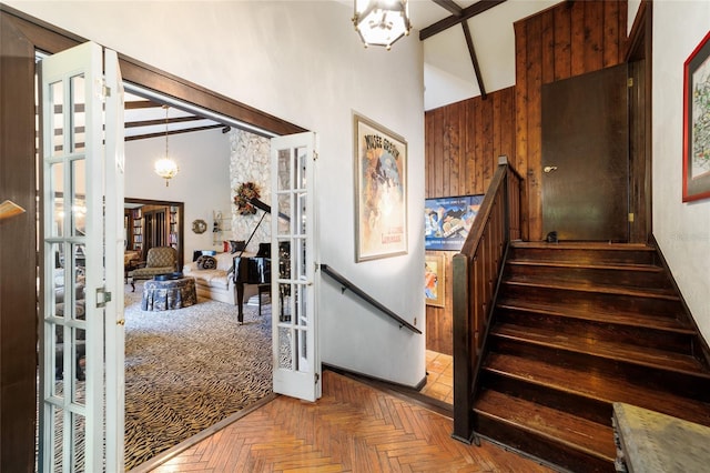 staircase with french doors, a high ceiling, and a notable chandelier