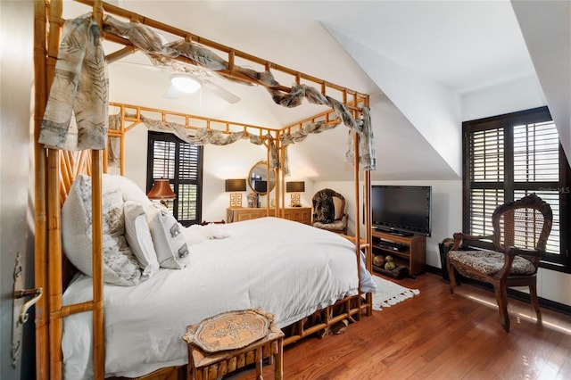 bedroom with multiple windows, vaulted ceiling, and wood finished floors