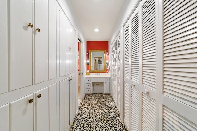 hallway with recessed lighting, a sink, and light floors